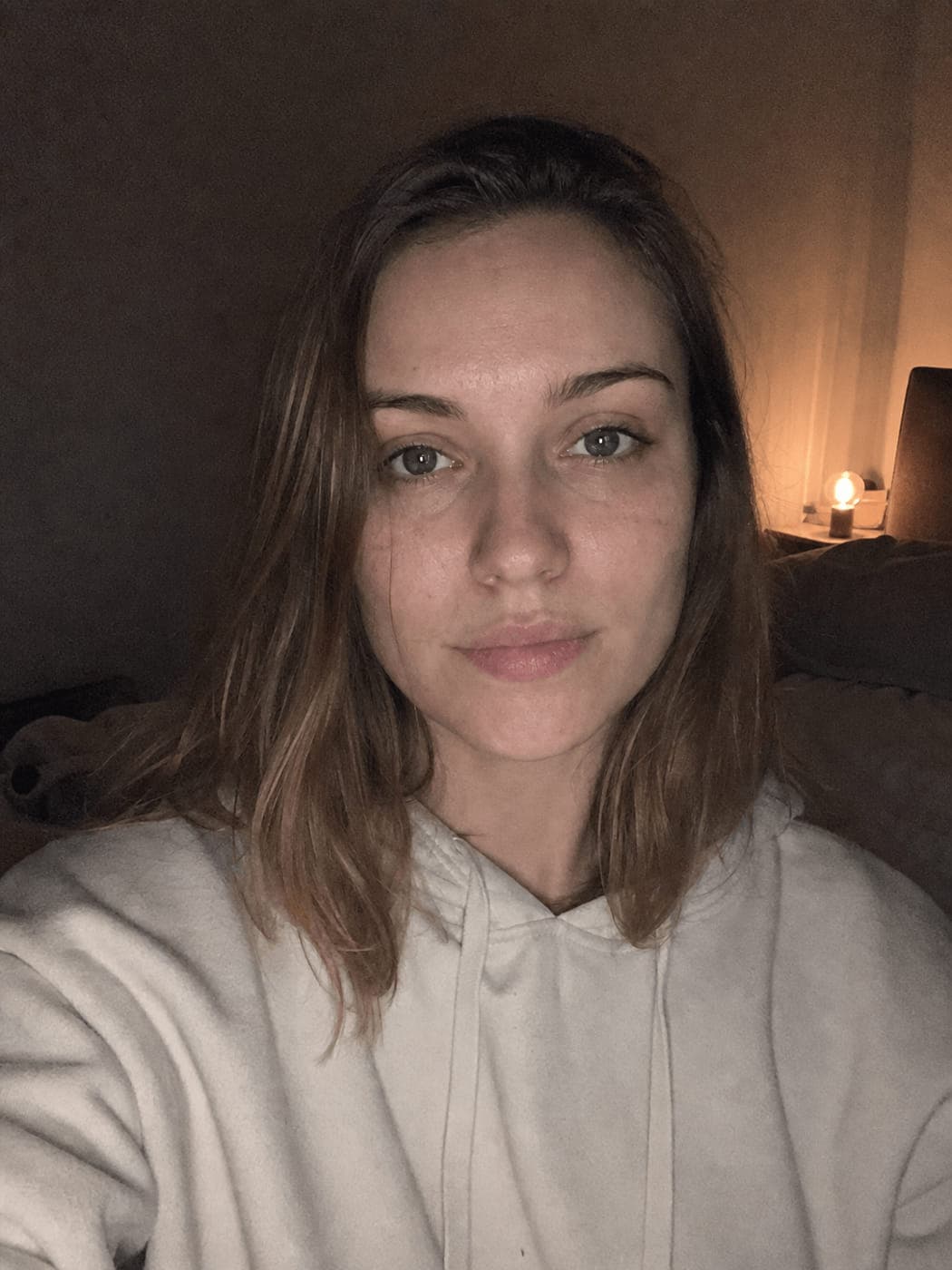 Selfie taken on a bed under a lamp at night